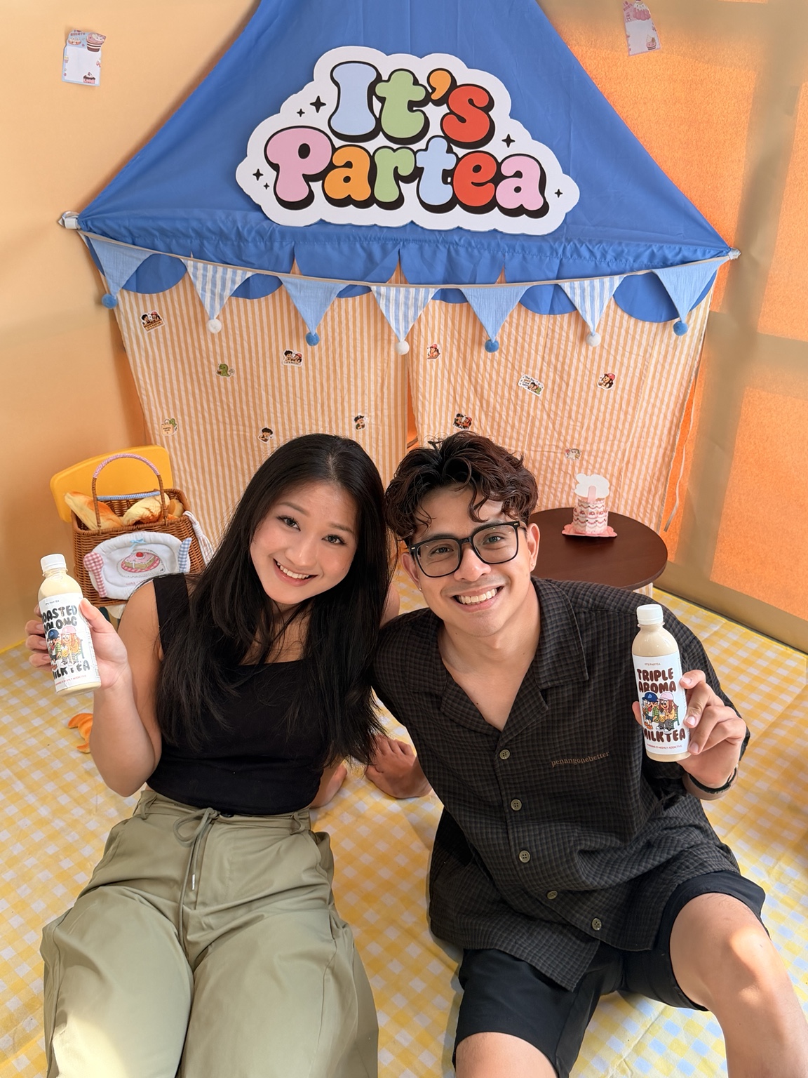 It’s Partea founders Tee Hoong and Jia Wen with their bottled milk teas beneath the It’s Partea sign